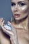 Portrait of chic gorgeous blue-eyed woman with glittering artistic make-up looking straight and holding a shining gem in her palm