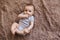 Portrait of a child 4 months old lying on the bed and looking. Charming child with dark eyes lying on back, portrait of baby boy