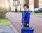 Portrait of Child with bored face holding plastic toy and carrying bag waiting for school bus, Unhappy Pupil of primary school