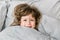 Portrait of child girl with big blue eyes in bed. Little girl smilling and having fun in bed. Funny quarantine house isolation.