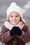 Portrait of a child of a little girl in a white warm hat and in a scarf