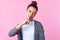 Portrait of childish cute brunette teenage girl picking nose pulling out boogers. indoor studio shot, pink background