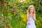 Portrait of children in an apple orchard. Little girl in blue striped dress, holding apples in her hands