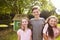 Portrait Of Children Standing In Garden Next To Playhouse