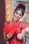 Portrait of Chinese woman wear traditional dress cheongsam and holding Red envelope or gife voucher for reward at chinese shrine