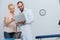 portrait of chiropractor in white coat and female patient using laptop