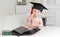 Portrait of clever baby in graduation cap posing with books