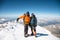 Portrait climber in a down jacket and harness he is standing next to his friend on the way to the top of a snow-capped