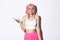 Portrait of clueless cute girl in pink wig shrugging, looking unaware, standing in halloween costume with bright makeup