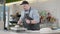 Portrait of concentrated Caucasian man in apron cutting and weighing raw dough on commercial kitchen. Professional chef