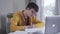 Portrait of concentrated Caucasian teen boy in eyeglasses doing homework. Smart college student reading from laptop and