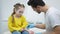 Portrait of concentrated scared girl sitting on medical couch as blurred doctor disinfecting hand and opening syringe