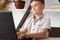 Portrait of a concentrated schoolboy typing on the keyboard of a laptop at home or playing a virtual computer game