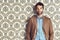 Portrait, confidence and man in suit for fashion on a vintage wallpaper background isolated in studio. Face, style and