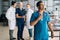 Portrait of confident African-American male doctor in blue uniform standing in medical meeting office, looking away.