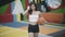 Portrait of confident brunette young sportswoman walking with basketball ball looking at camera. Slim beautiful