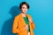 Portrait of confident business lady orange blazer green t shirt posing for vogue fashionable magazine isolated on blue