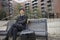 Portrait of confident businessman with luggage sitting on bench against buildings