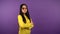 Portrait of confident calm asian woman in yellow sweater. woman on purple isolated background. the woman folded her arms