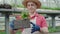 Portrait of confident Caucasian biologist examining flowers in box and smiling. Mid-adult man in straw hat checking