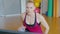 Portrait of confident Caucasian sports trainer talking at laptop and showing thumb up. Blond athletic woman training