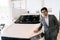 Portrait of confident customer male in business suit touching hood of new car standing looking at camera with positive