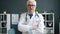 Portrait of confident experienced doctor standing in office room with arms crossed