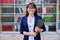 Portrait of confident female teacher holding laptop inside library