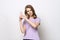 Portrait of confident girl in purple t shirt holding hands like gun, playing shooter