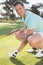 Portrait of confident golfer man placing golf ball on tee