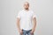 Portrait of confident good-looking bald caucasian guy wearing casual t-shirt and jeans, holding hands in pockets