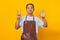 Portrait of confident handsome Asian young man wearing apron pointing with finger number seven with angry expression