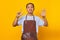 Portrait of confident handsome Asian young man wearing apron pointing with finger number seven with angry expression