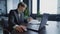 Portrait of confident handsome brunette male employee sitting in office analyzing documents typing on laptop keyboard