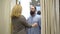 Portrait of confident handsome Caucasian man opening curtain in shop dressing room and woman adjusting his shirt