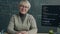 Portrait of confident lady online school tutor sitting in classroom with computer and chalkboard