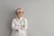 Portrait of confident mature businesswoman in shirt and glasses standing by grey copy space wall