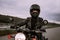 Portrait of confident motorcyclist woman in motorcycle helmet. Young driver biker looking away outdoors alone on highway