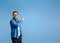 Portrait of confident salesman pointing at product with copy space while standing on blue background