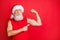 Portrait of confident santa claus in cap hat showing his triceps gym training effect wearing trendy sports wear 