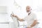 Portrait of confident senior dentist sitting on chair at dental clinic