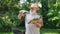 Portrait of confident senior farmer with shovel on shoulder and harvest looking at camera talking in slow motion