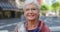 Portrait of confident senior woman in a cool and trendy scarf, showing cheerful facial expression in city. Closeup