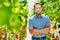 Portrait of confident supervisor standing with arms crossed against tomatoes in greenhouse