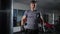 Portrait of confident tired satisfied man in boxing gloves posing in gym at punching bag. Medium shot of handsome