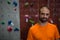 Portrait of confident trainer standing by climbing wall in gym