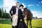 Portrait of confident well-dressed couple standing with horse on field