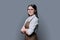 Portrait of confident young woman worker in apron on grey background