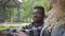 Portrait confidient pretty blond woman and handsome African American man talking sitting under an old tree in the park