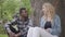 Portrait confidient pretty blond woman and handsome African American man talking sitting under an old tree in the park